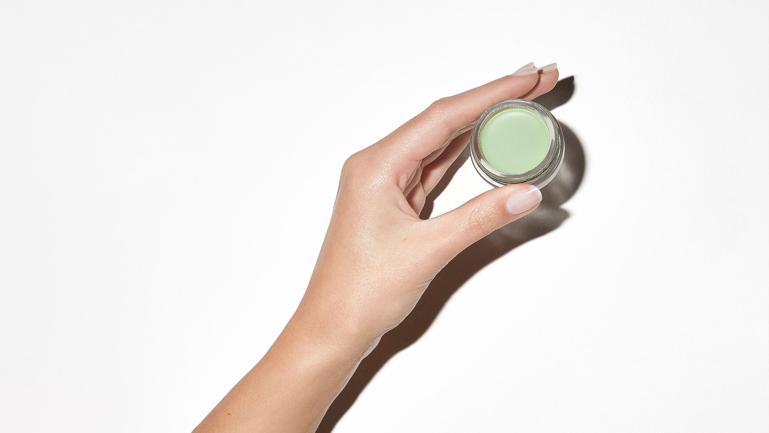 superlumious-green-concealer.jpg Model holding a pot of our Superluminous Redness Corrector